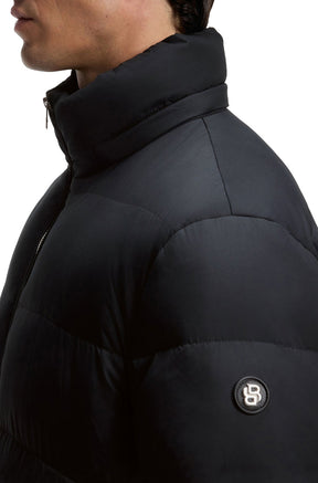 Gros plan de côté du manteau d'hiver matelassé noir avec col rembourré et écusson sur la manche pour homme par HUGO BOSS