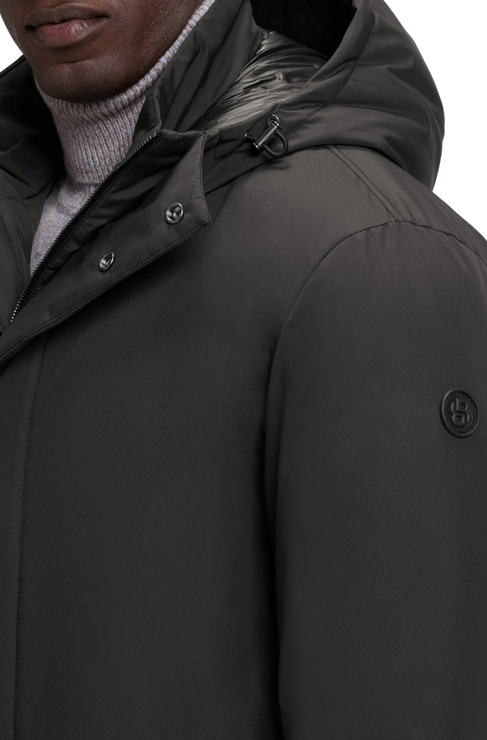 Détail de l'épaule du manteau d'hiver noir avec capuchon à cordon et logo sur la manche pour homme par HUGO BOSS