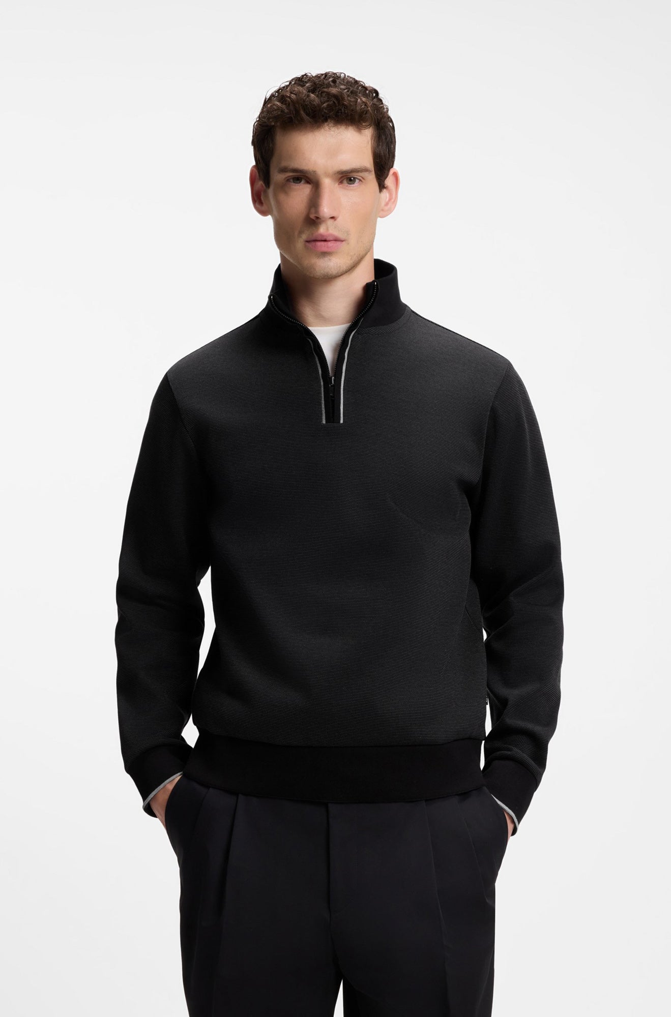 Men's black quarter-zip sweatshirt on model, with stand collar, textured body and ribbed hem, front view by HUGO BOSS