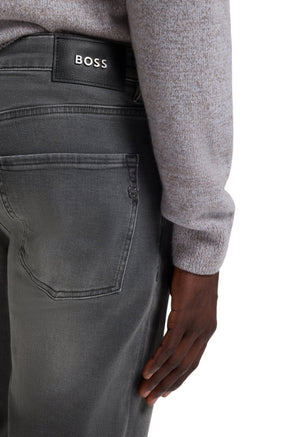 Men's back detail of gray straight-leg jeans with black BOSS patch, rear pocket, and metal emblem by HUGO BOSS