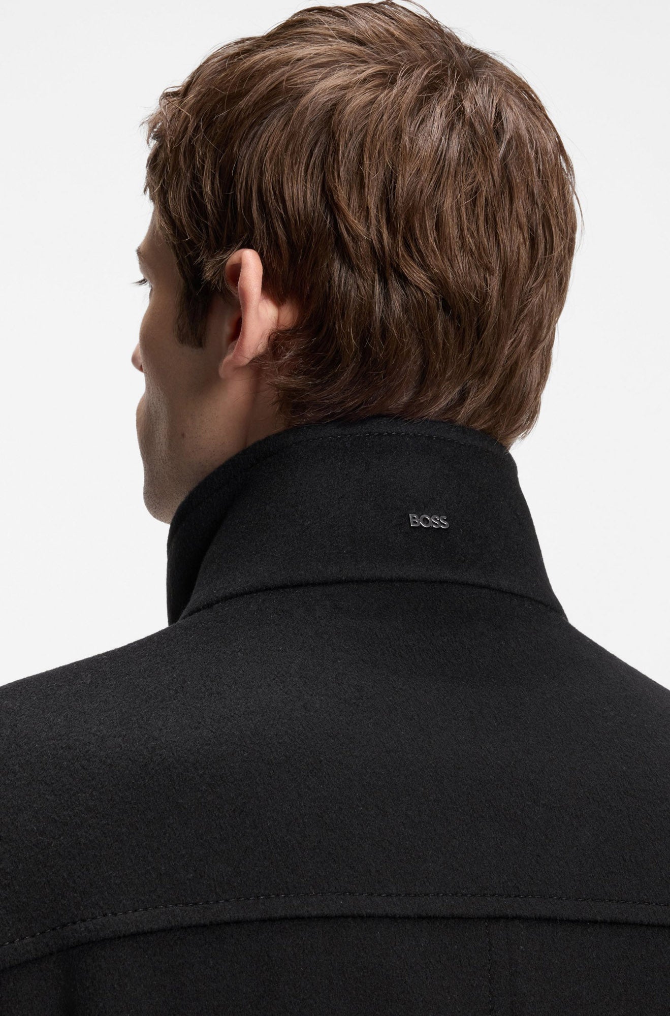 Men's back close-up of black winter coat collar with small metal BOSS logo and tonal stitching by HUGO BOSS