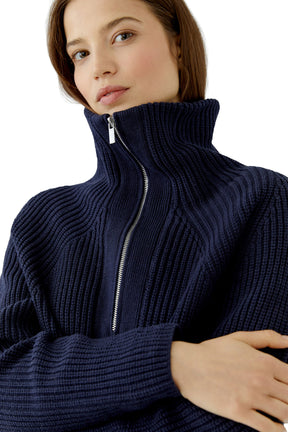 Women's close detail of navy ribbed knit sweater with raised zip collar and silver zipper teeth by Oui