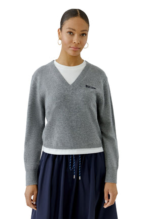 Oui women's front waist-up model view of gray V-neck knit long-sleeve knit sweater with black chest text and ribbed hem