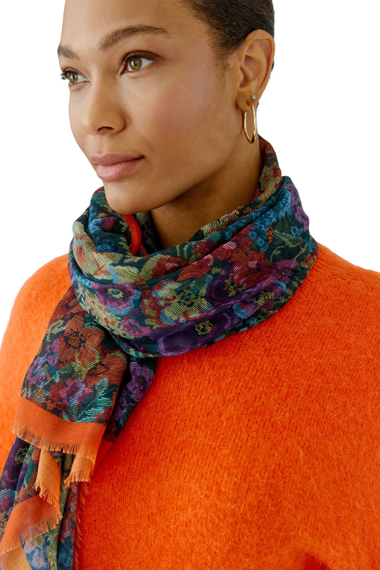 Women's model wearing multicolor floral scarf with orange border wrapped at the neck, front view by Oui