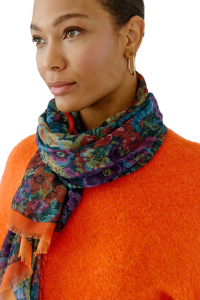 Women's model wearing multicolor floral scarf with orange border wrapped at the neck, front view by Oui