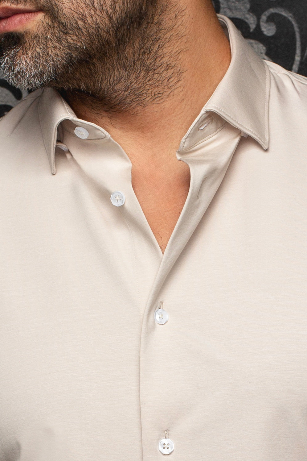 Gros plan du col de chemise beige pâle et de la patte ouverte à boutons blancs pour homme par Au Noir