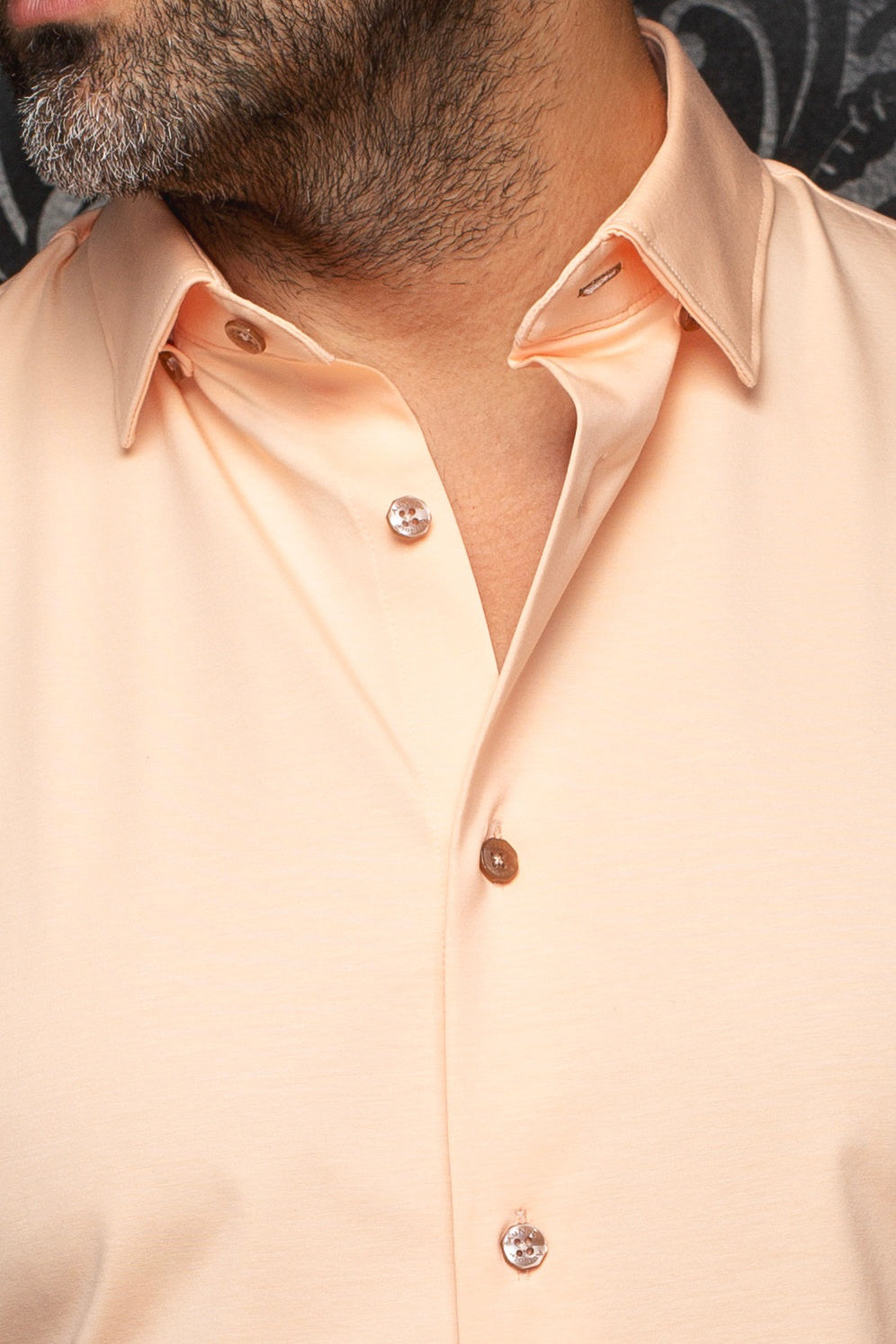 Col d’une chemise pêche avec tissu lisse et boutons bruns lustrés pour homme par Au Noir, en gros plan