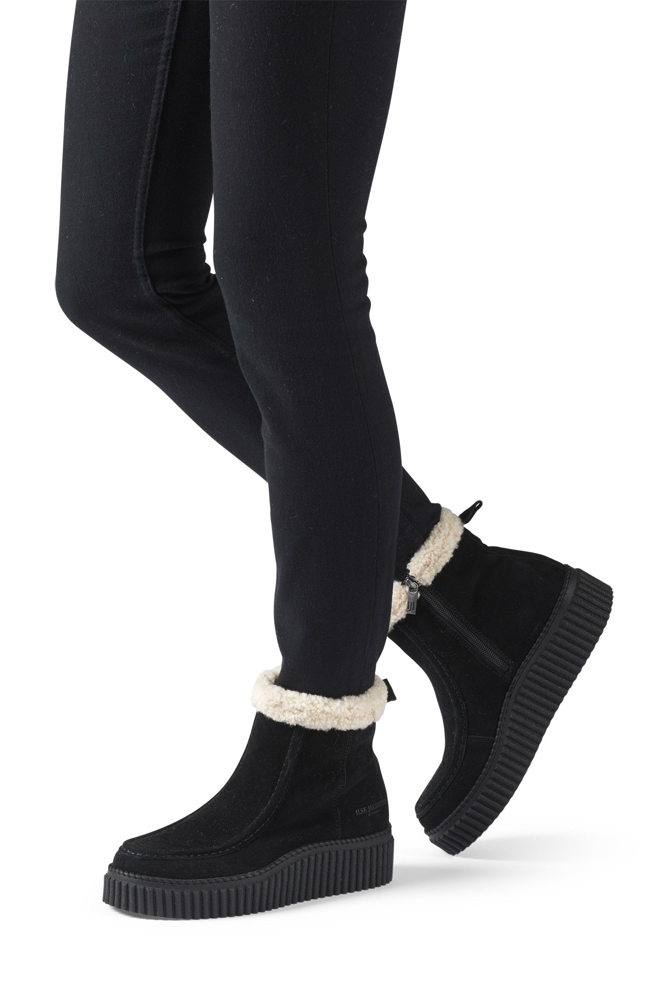 Ilse Jacobsen women's black ankle boots worn with black pants, showing cream cuff, side zipper, and thick ribbed sole