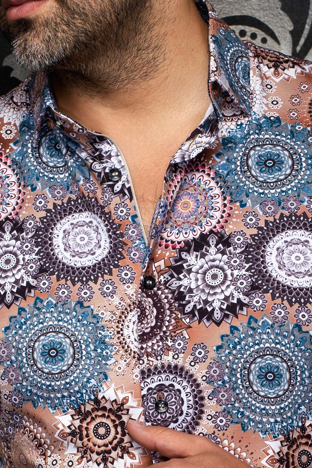 Gros plan du col et de la patte boutonnée noire d’une chemise beige à motifs sarcelle et blancs pour homme par Au Noir