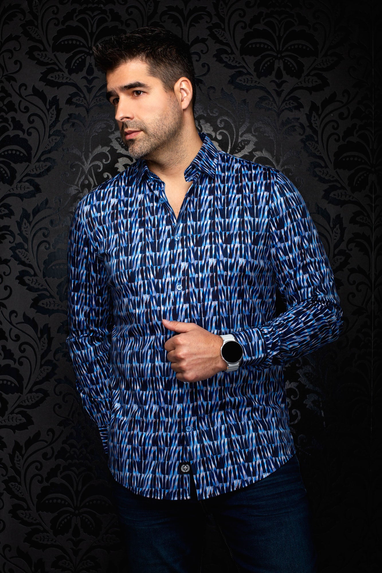 Men's angled front view of a blue abstract print button-up shirt with curved hem and long sleeves by Au Noir
