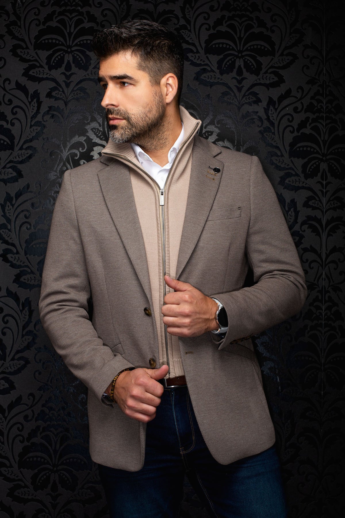 Veston taupe texturé à revers crantés, boutons bruns et épinglette pour homme par Au Noir, vue avant en angle