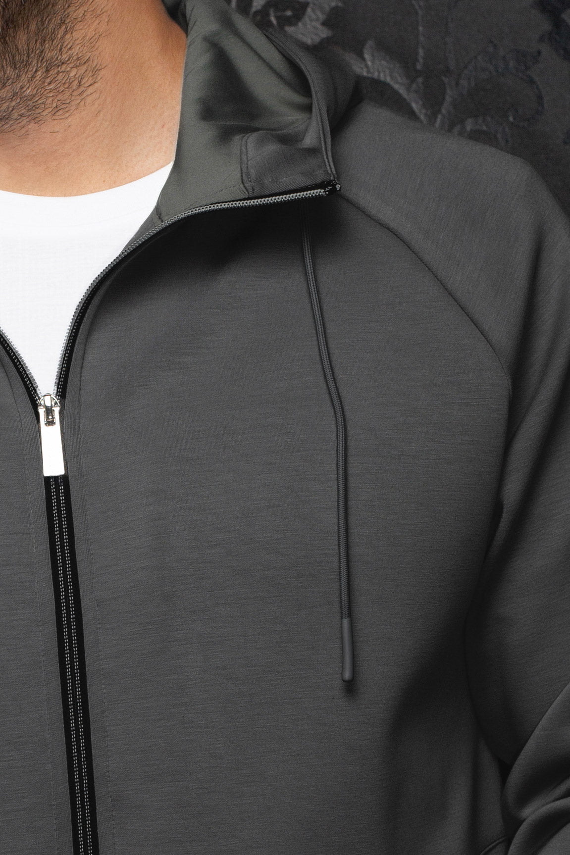Au Noir men's dark gray hooded zip sport jacket shown close-up with texture, raglan seam, drawcord and black zipper