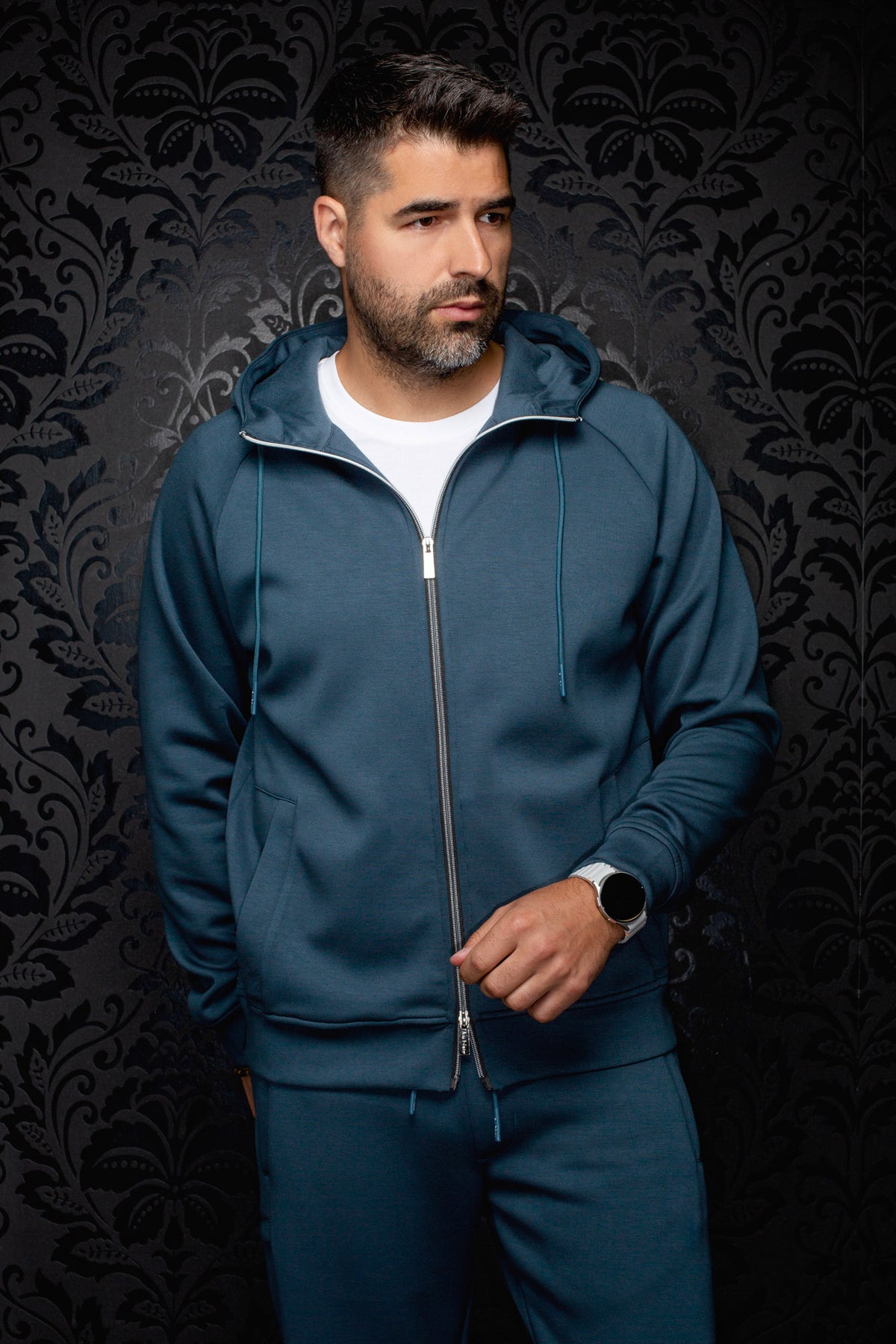 front view of Au Noir men's teal full-zip hooded sport jacket on model with drawstrings and split pockets