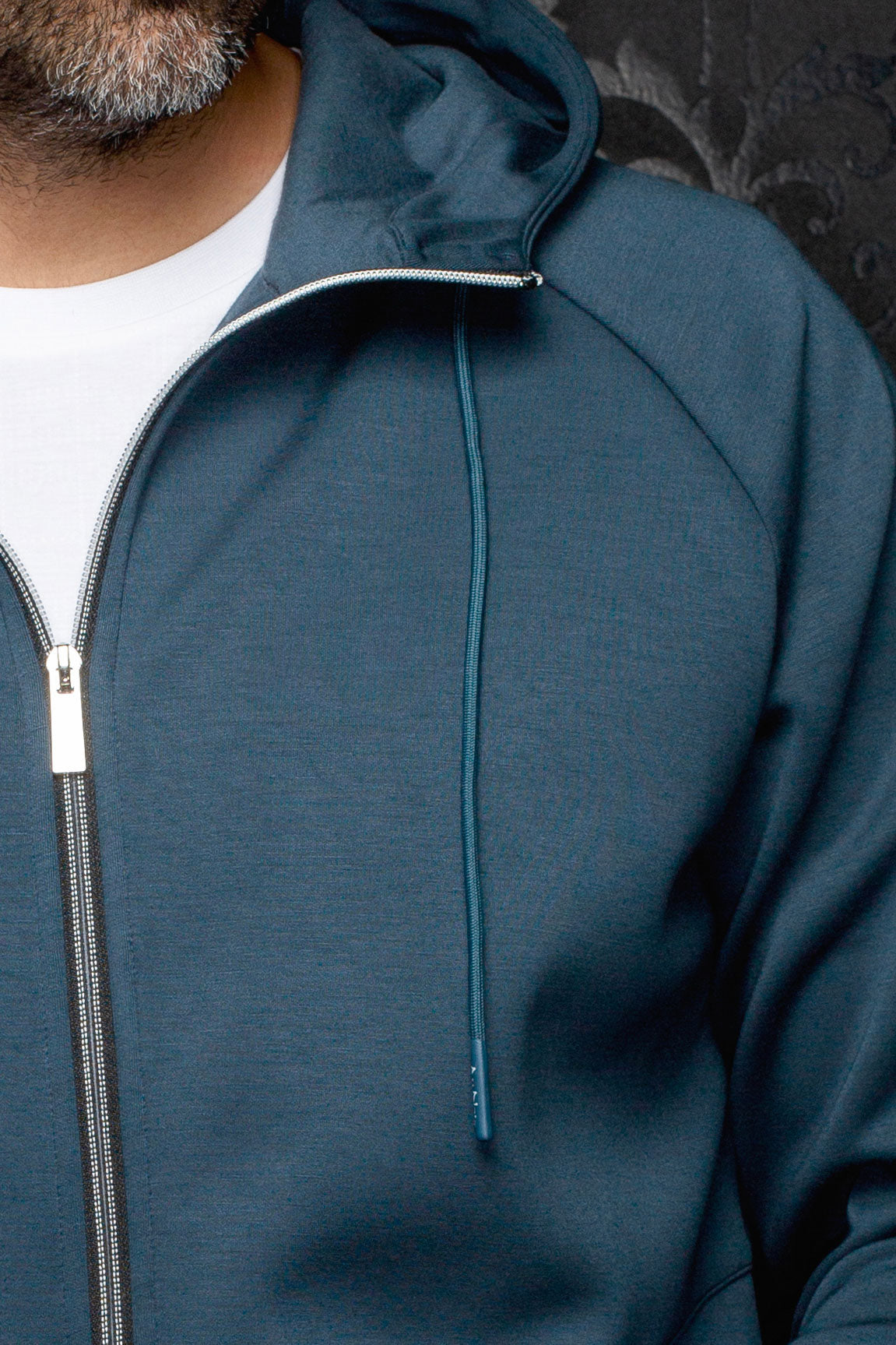 Au Noir men's teal hooded zip sport jacket shown close-up with raglan seam, drawstring and silver zipper