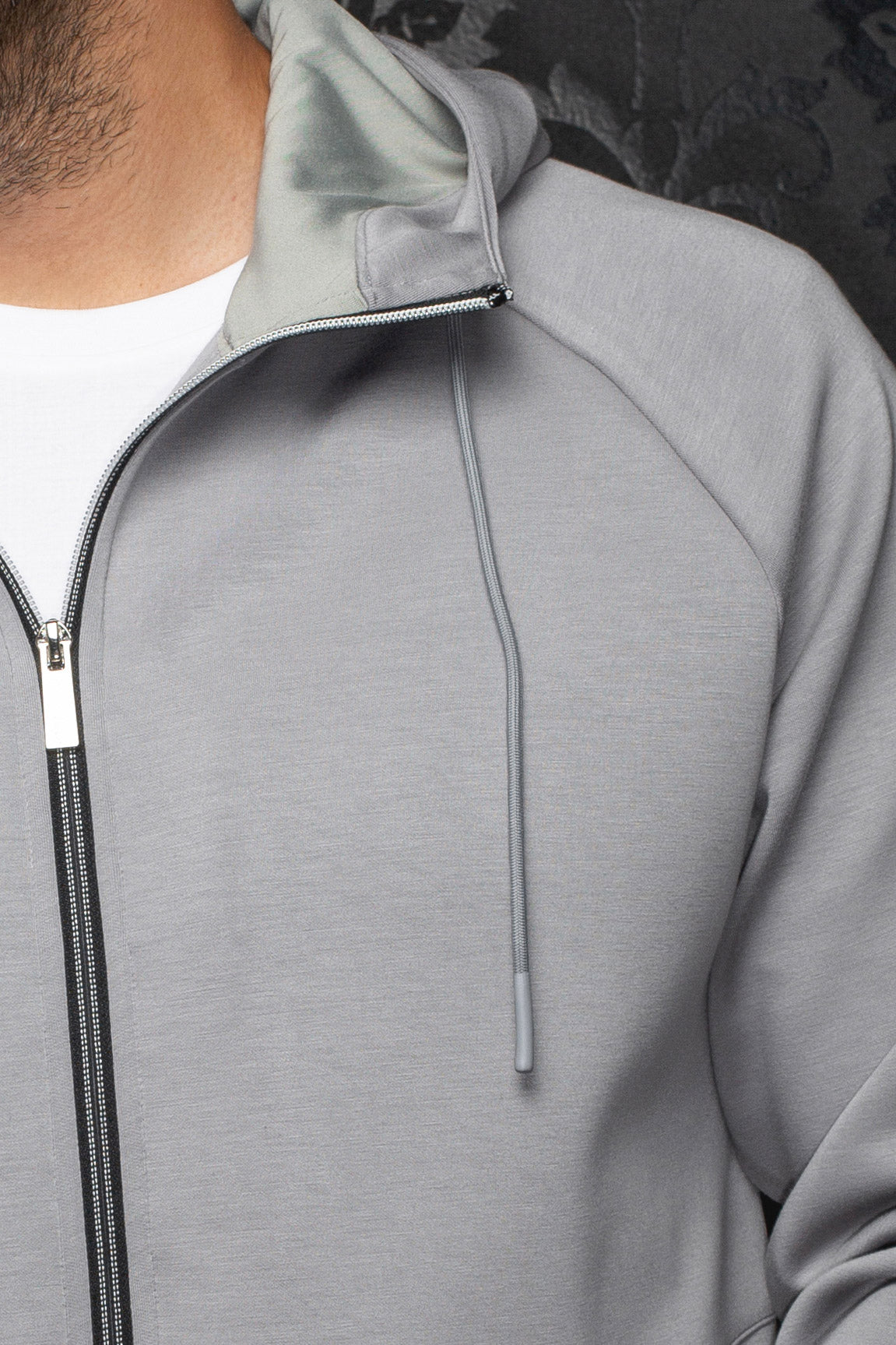 Au Noir men's light gray zip sport jacket with drawcord detail, black zipper tape and hood lining, close-up