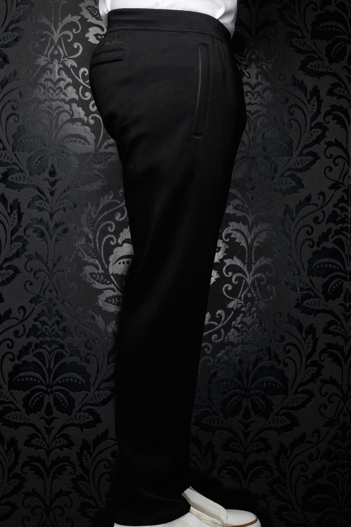 Au Noir men's black jogging pants with vertical pocket detail, drawstring and elastic waistband shown from the side