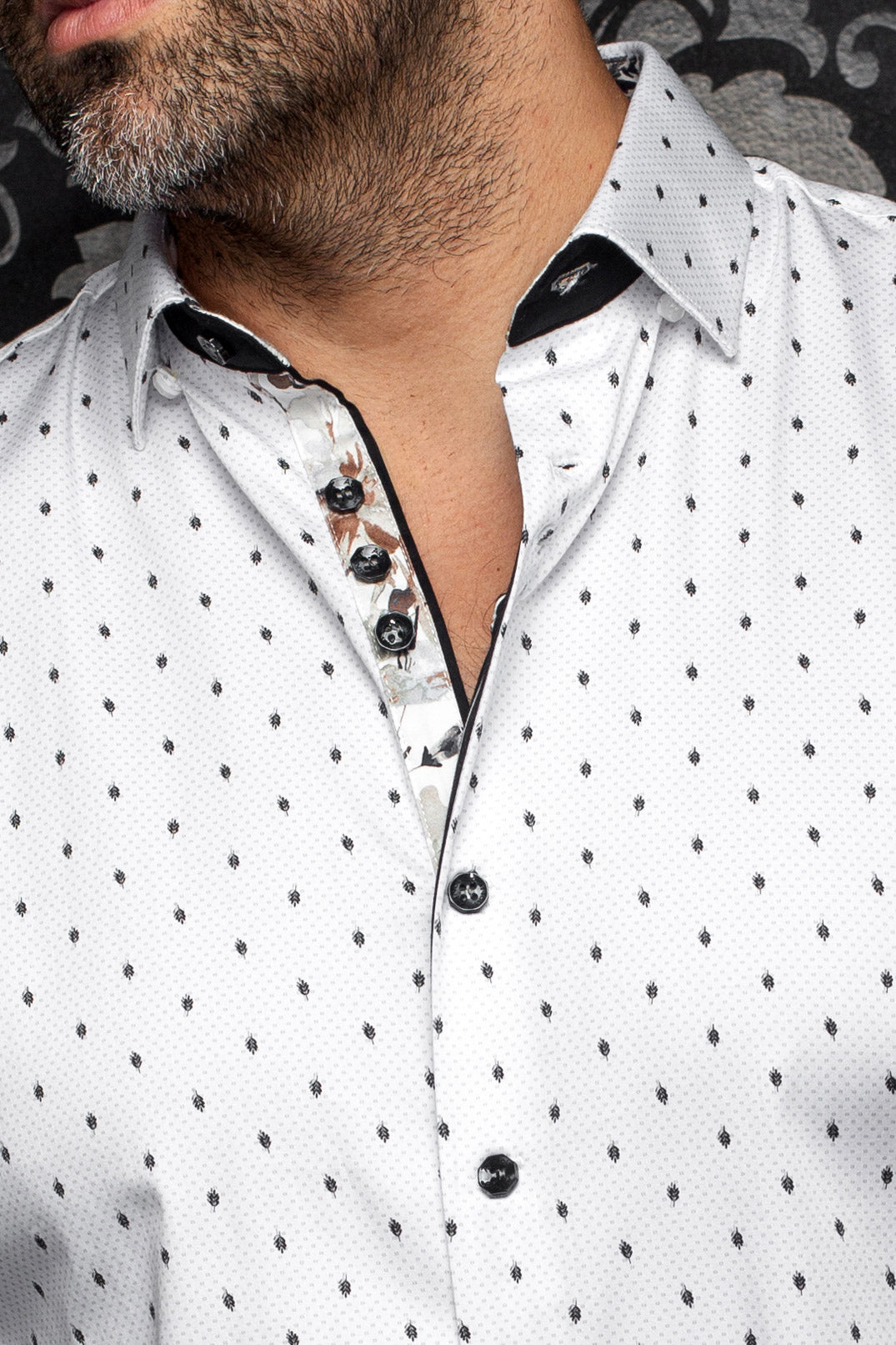 Gros plan du col de chemise blanche imprimée avec patte intérieure fleurie et boutons noirs pour homme par Au Noir