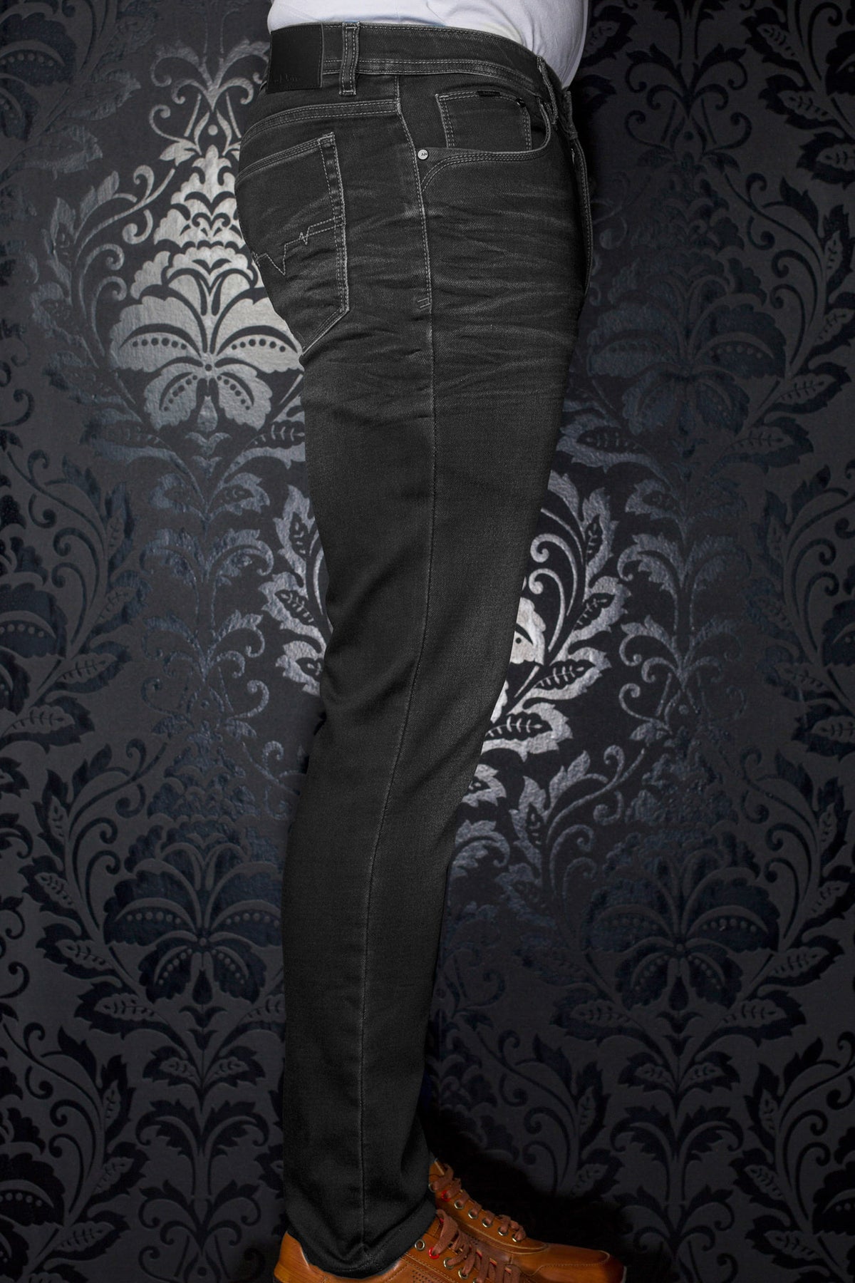 Jean noir vu de côté avec écusson à la taille, poche arrière et surpiqûres contrastantes pour homme par Au Noir