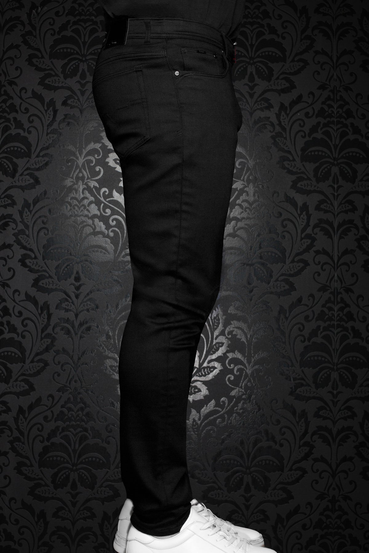 Vue de côté de jean noirs ajustés sur mannequin avec jambe étroite, passants et poche avant pour homme par Au Noir