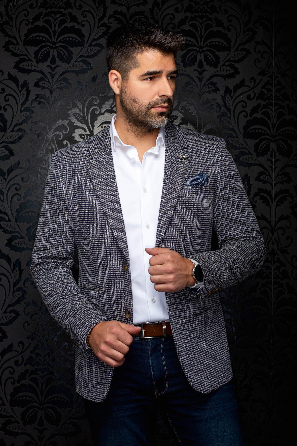 Sur mannequin de face, le veston texturé bleu marine à revers crantés et pochette bleue pour homme par Au Noir
