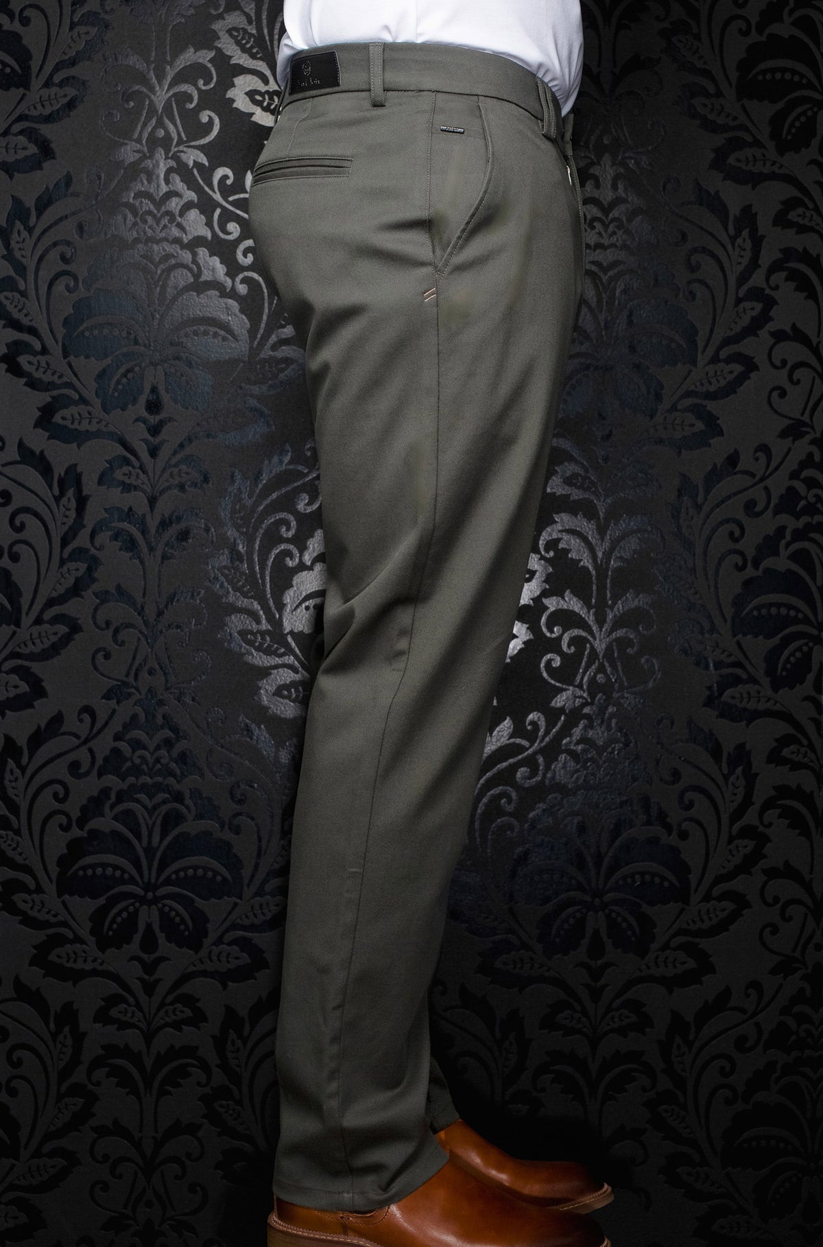 Vue de côté d’un pantalon chino vert olive avec jambe droite, passants et poche passepoilée pour homme par Au Noir