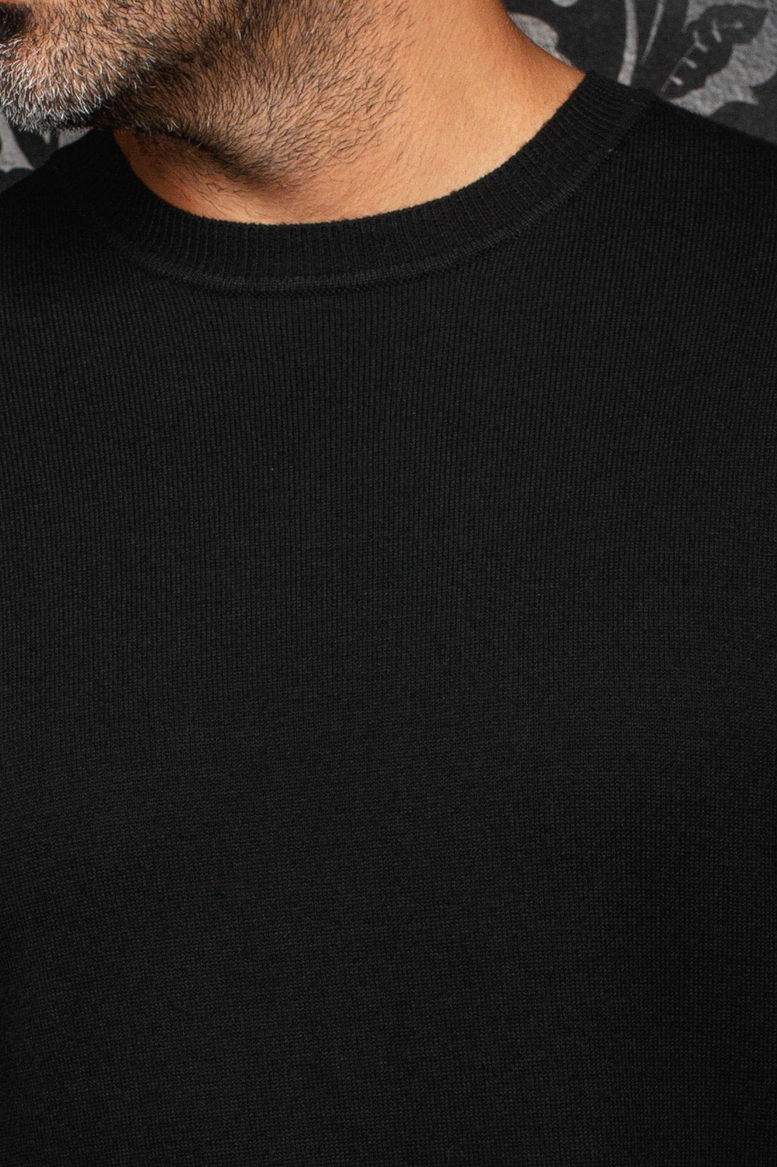Gros plan d’une chandail en cachemire noir en tricot fin avec devant uni et col rond côtelé pour homme par Au Noir