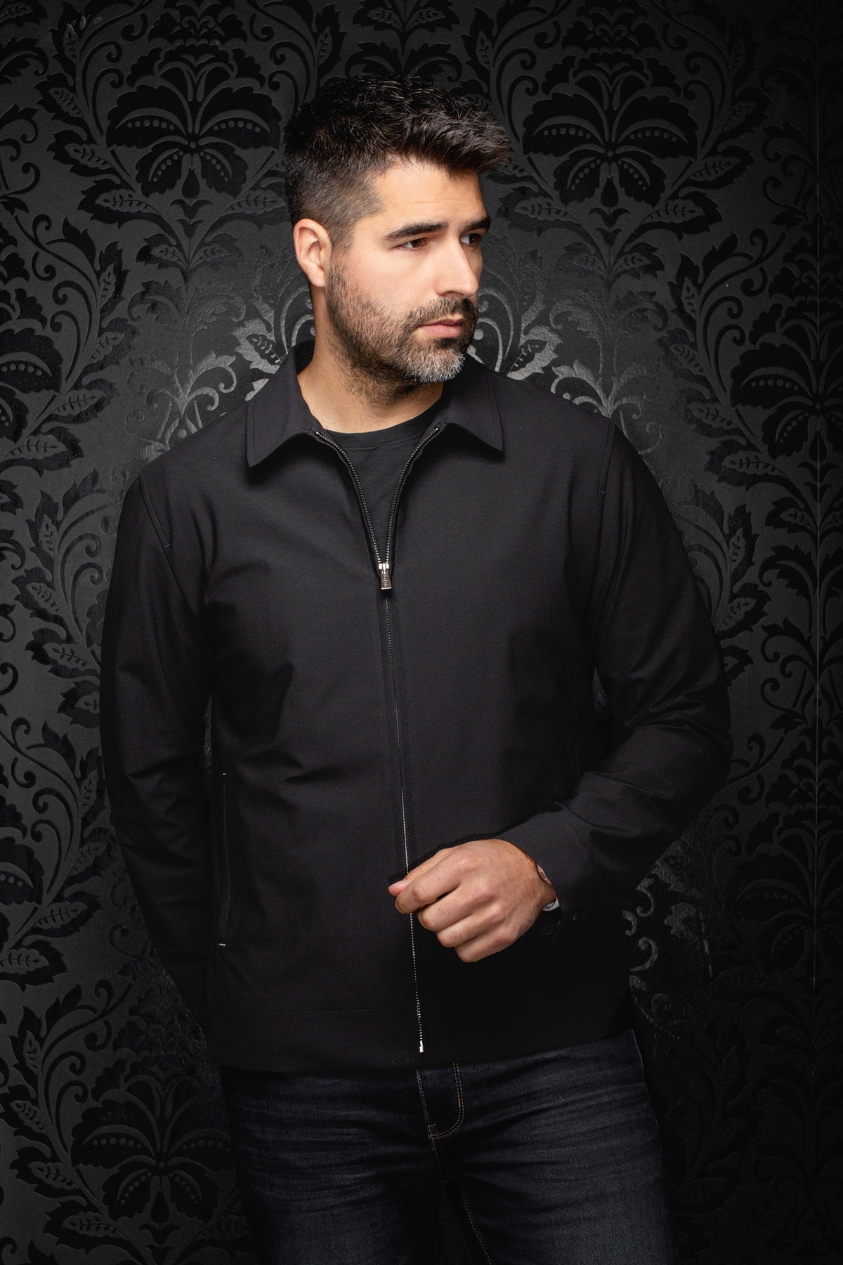 Vue de face d’un coupe-vent mi-saison style bomber noire zippé avec manches longues et col pointu pour homme par Au Noir