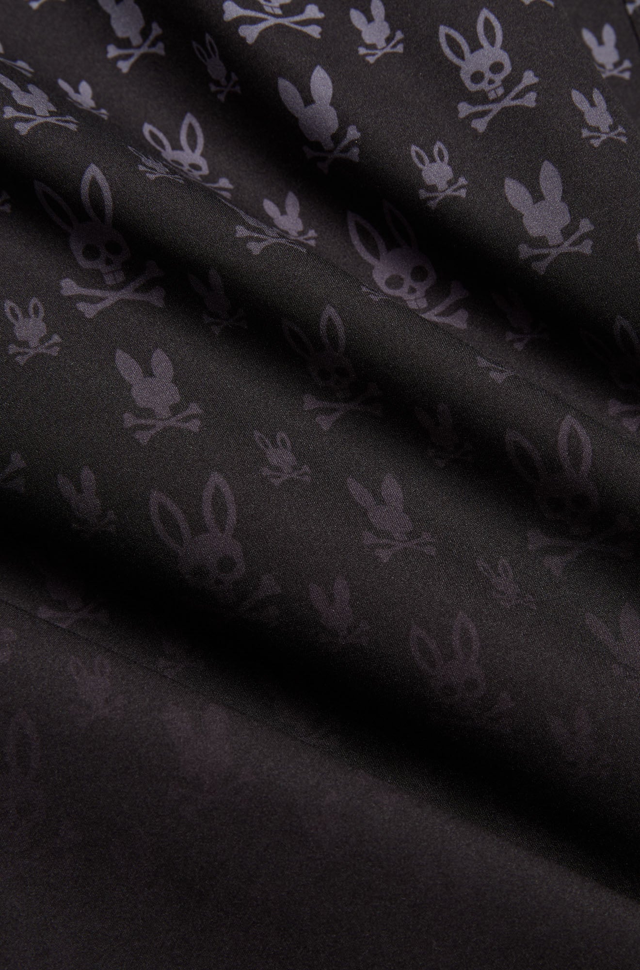 Short maillot noir à motif lapin tête de mort gris foncé et texture tissée lisse pour homme par Psycho Bunny, en gros plan