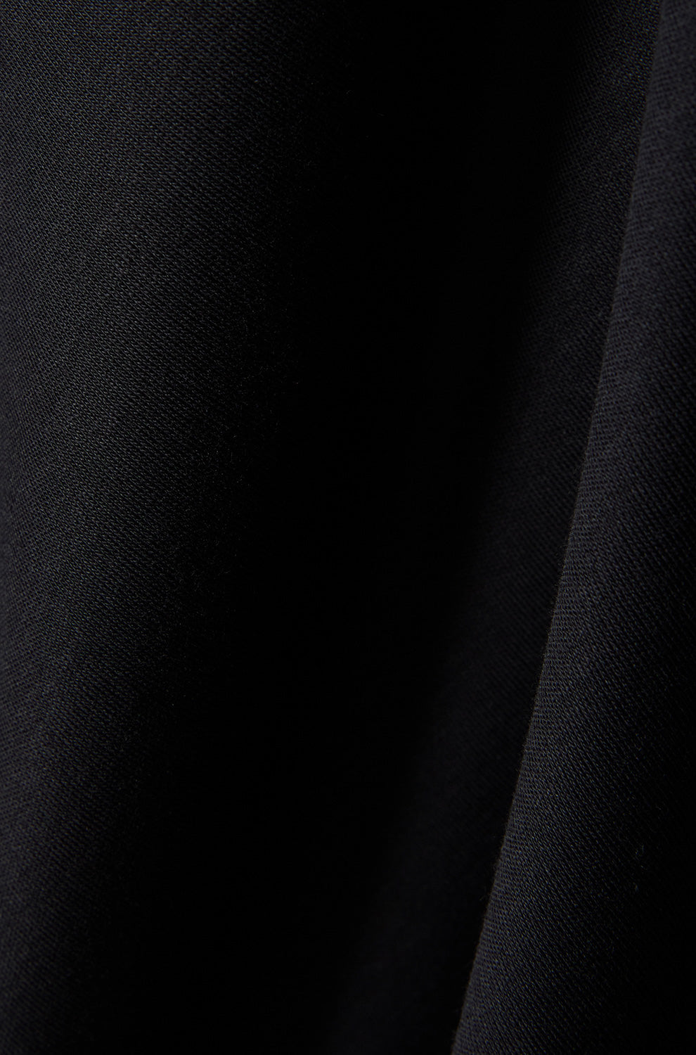 Tissu noir du polo montrant une texture tricot fine et une couture foncée pour homme par Psycho Bunny, en gros plan