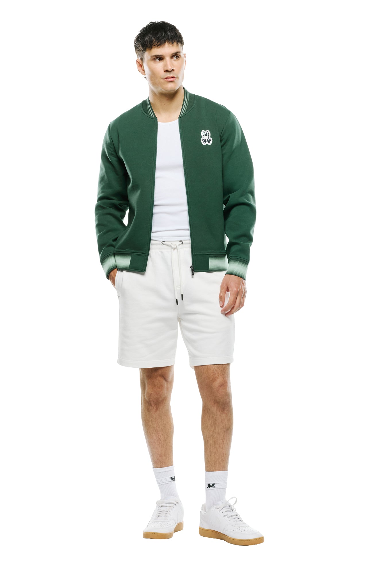 Men's full front model view of dark green zip bomber jacket with light green striped rib hem and cuffs by Psycho Bunny