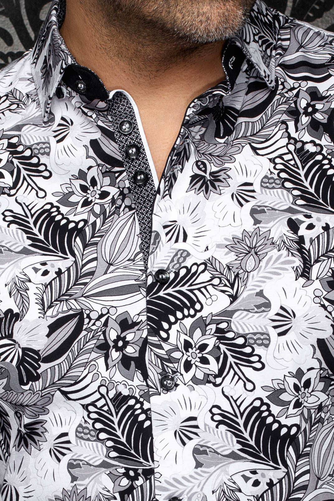 Gros plan du col de chemise blanche florale, des boutons noirs et de la patte contrastante pour homme par Au Noir