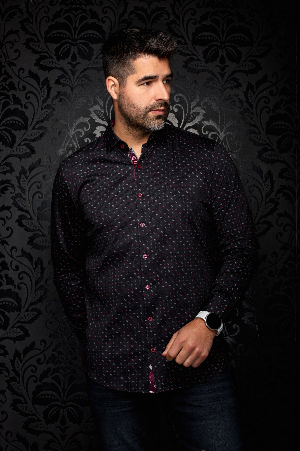 Sur mannequin de face, la chemise noire à boutons rouges et petit motif rouge et gris pour homme par Au Noir