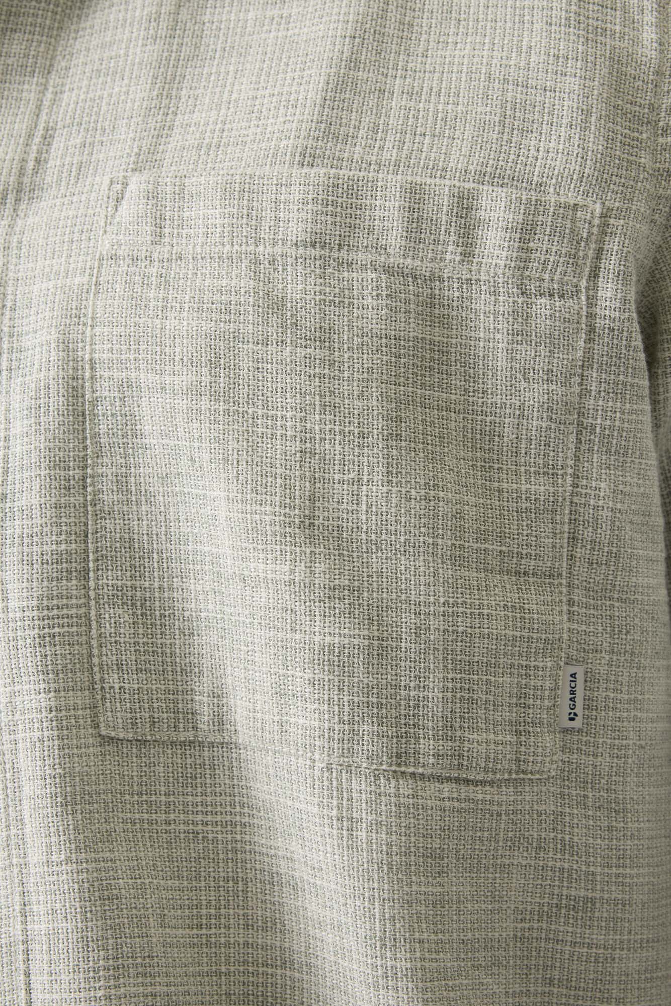 Détail d’une poche poitrine sur surchemise beige texturée avec petite étiquette logo pour homme par Garcia
