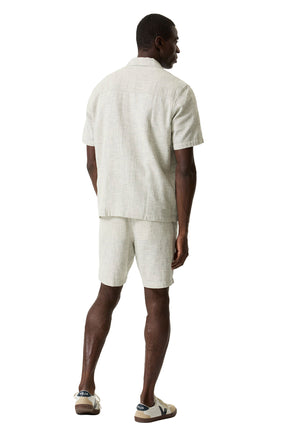 Vue arrière sur modèle de la short jambe droite beige pâle texturée, porté avec une chemise assortie à manches courtes