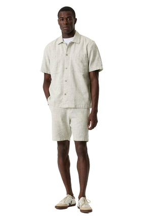 Vue avant sur modèle de la short jambe droite beige pâle texturée, porté avec une chemise assortie à manches courtes