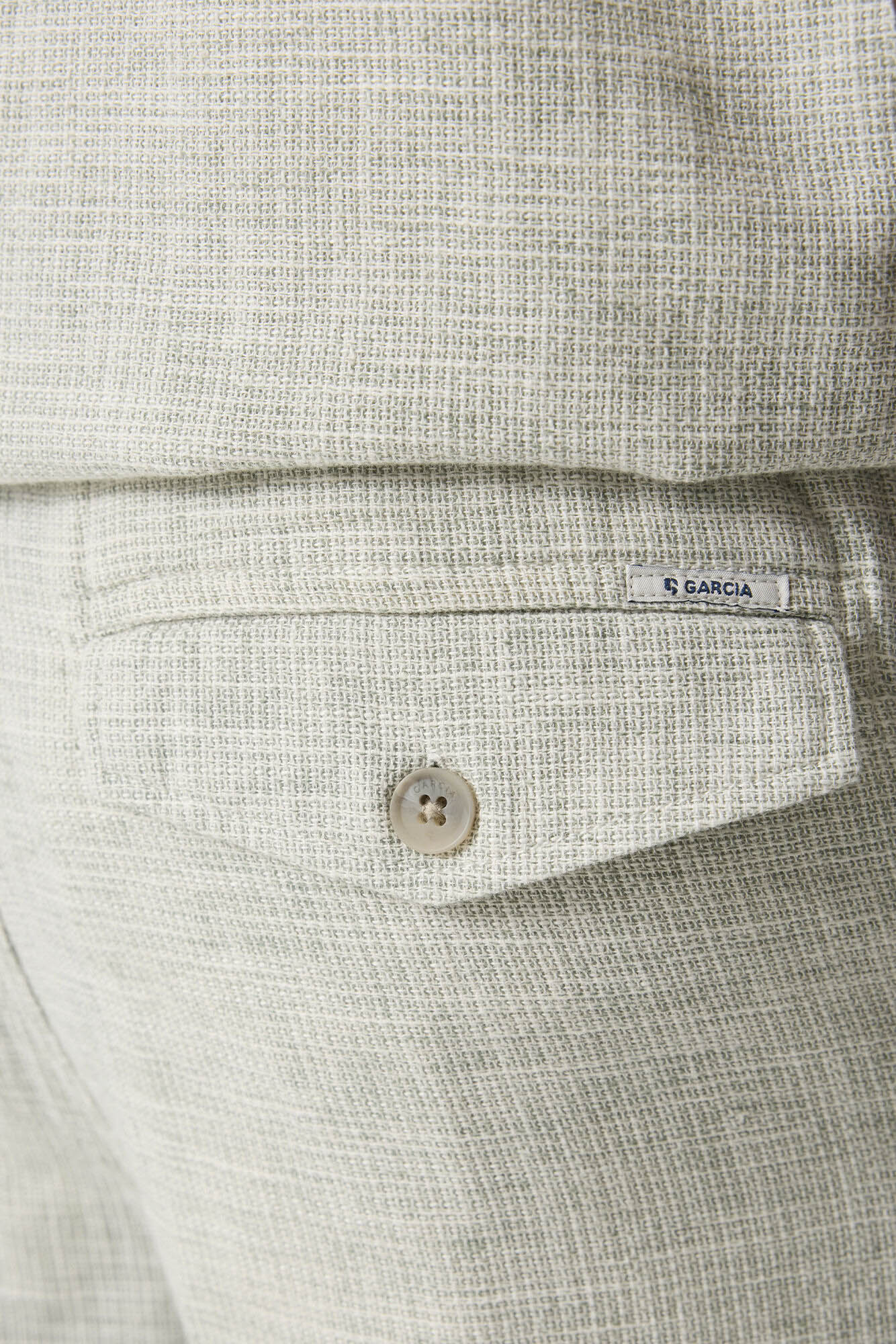 Short jambe droite beige pâle texturée avec poche arrière à rabat, bouton et petite étiquette Garcia, en gros plan