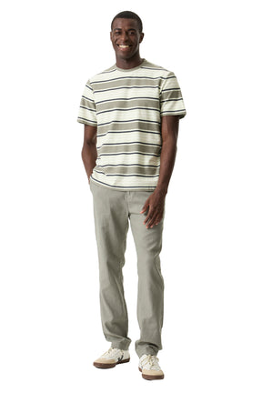 Autre vue avant sur mannequin du pantalon droit olive pâle porté avec un T-Shirt rayé et des espadrilles pour homme