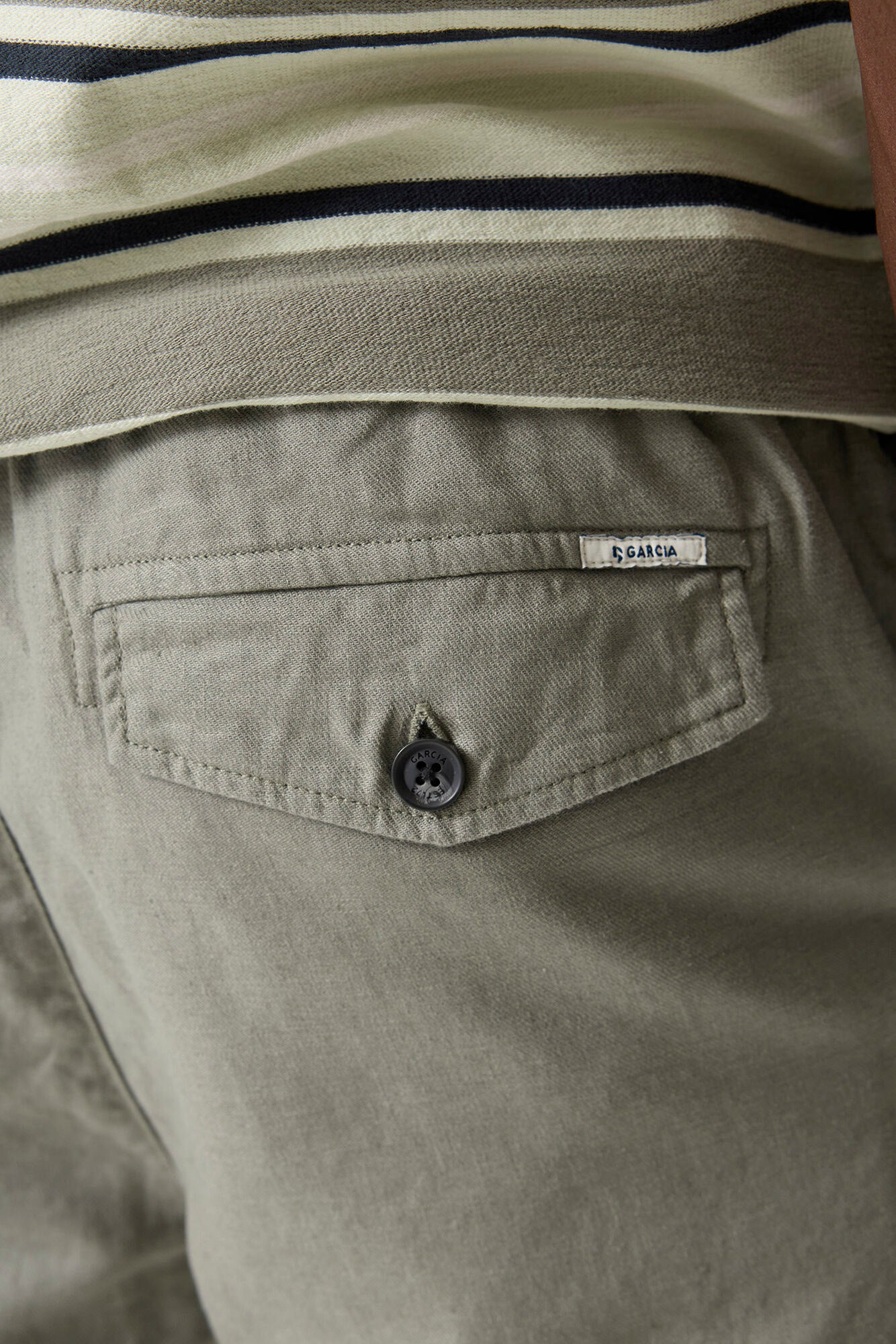 Gros plan sur la poche arrière à rabat du pantalon olive pâle avec bouton noir et étiquette Garcia pour homme