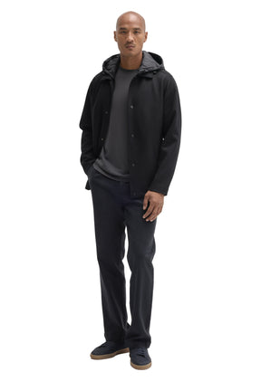 Men's full-body front view of black hooded snap-front jacket styled open over dark layers by Robert Barakett