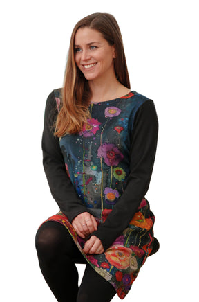 Women's seated front view of dark teal floral long-sleeve dress with black round neckline by Rien ne se perd, tout se crée