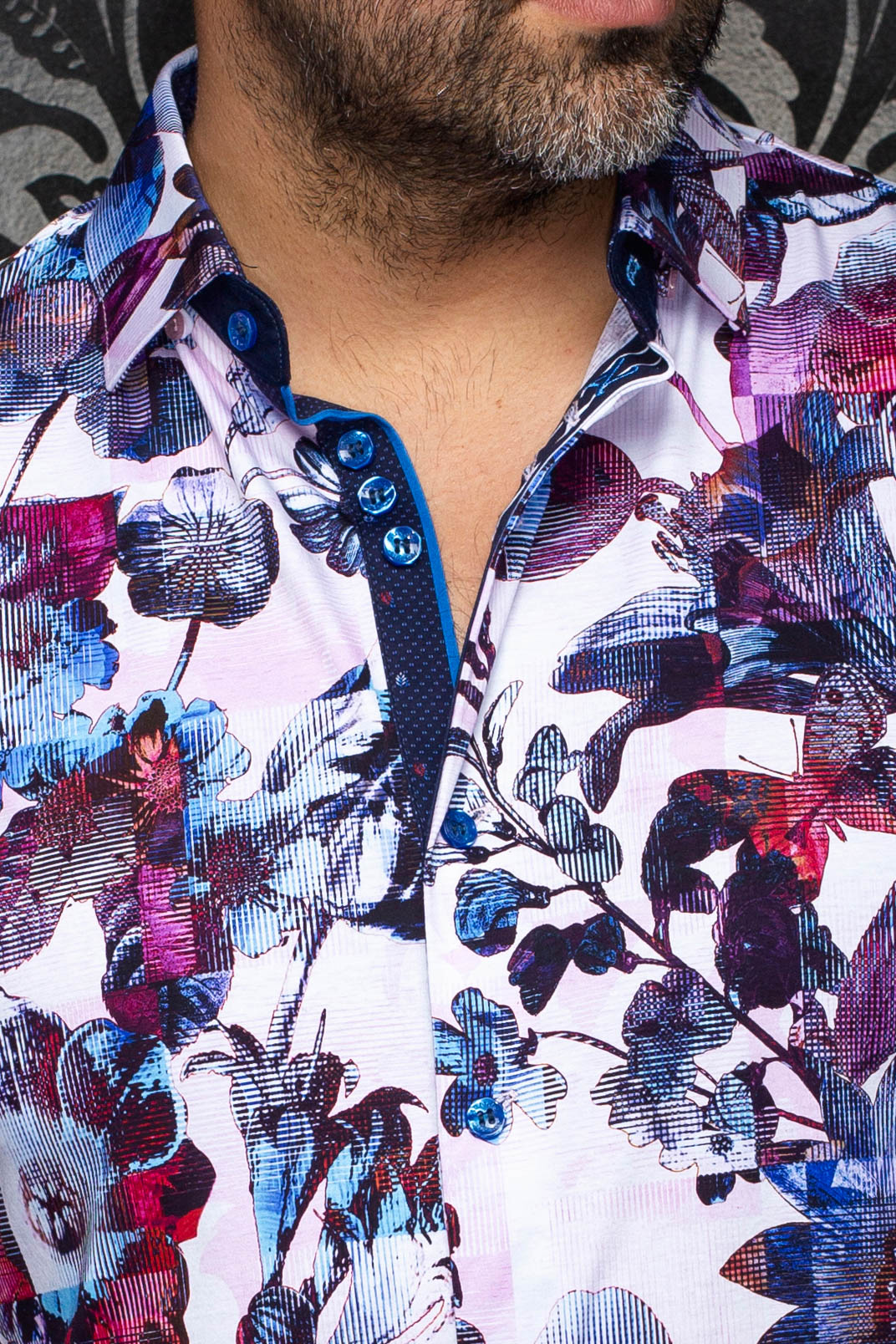 Gros plan d’une chemise boutonnée rose pâle à fleurs, patte marine et boutons bleus pour homme par Au Noir