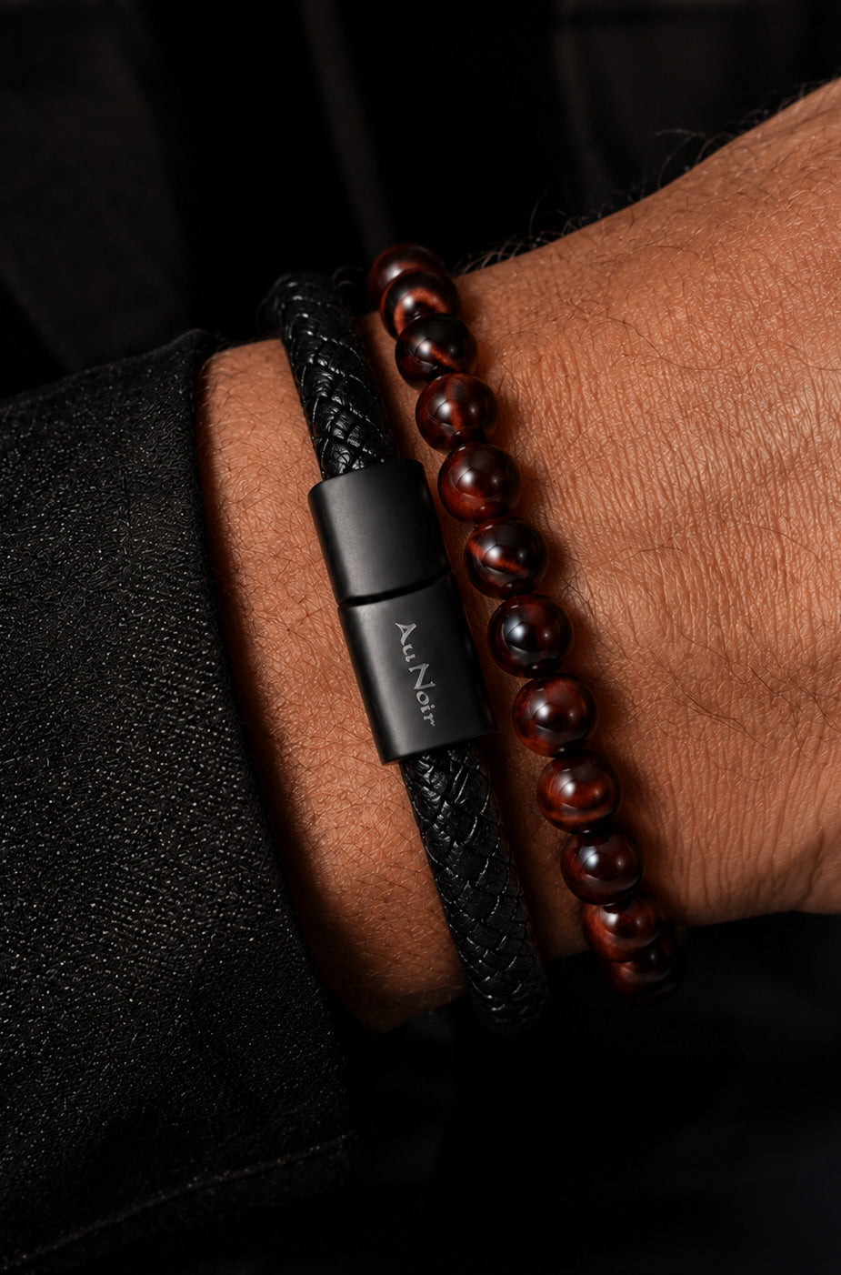 Gros plan du bracelet noir tressé et brun rougeâtre à perles au poignet, fermoir logo avec bracelets pour homme par Au Noir