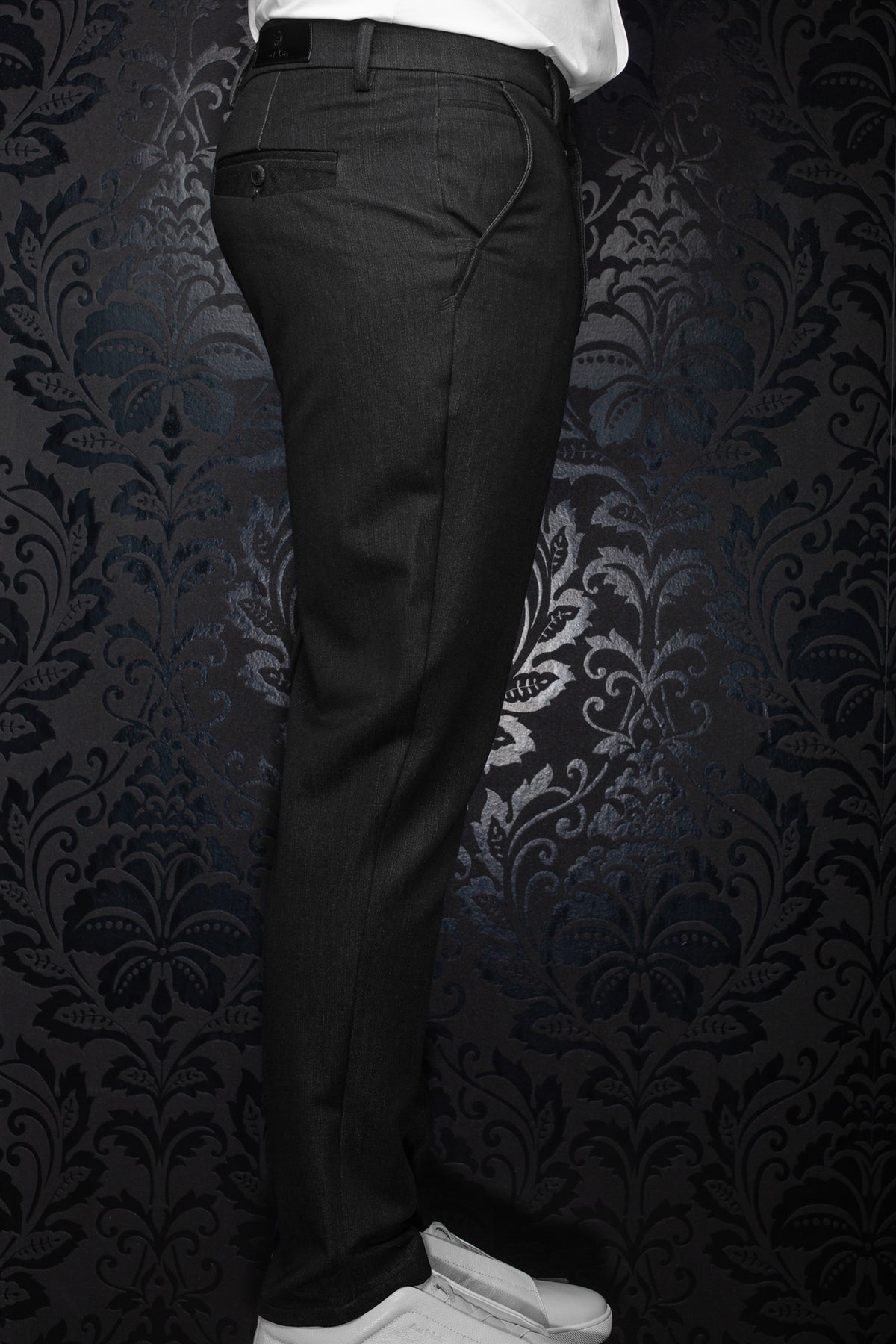 Vue de côté d’un pantalon noir avec couture courbée, poche passepoilée arrière et passants pour homme par Au Noir