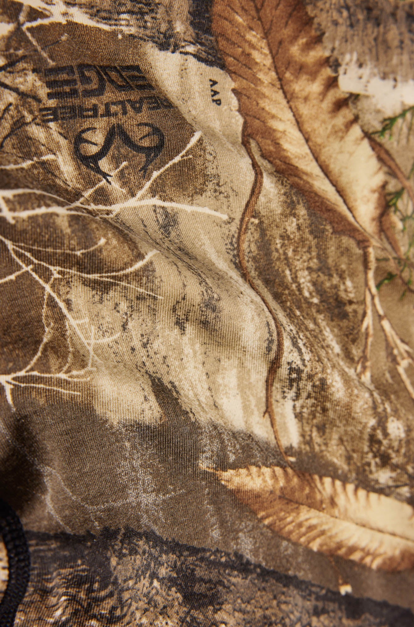 Détail rapproché du tissu camouflage brun en sous-vêtement avec feuilles, branches et marques Realtree pour homme par Saxx