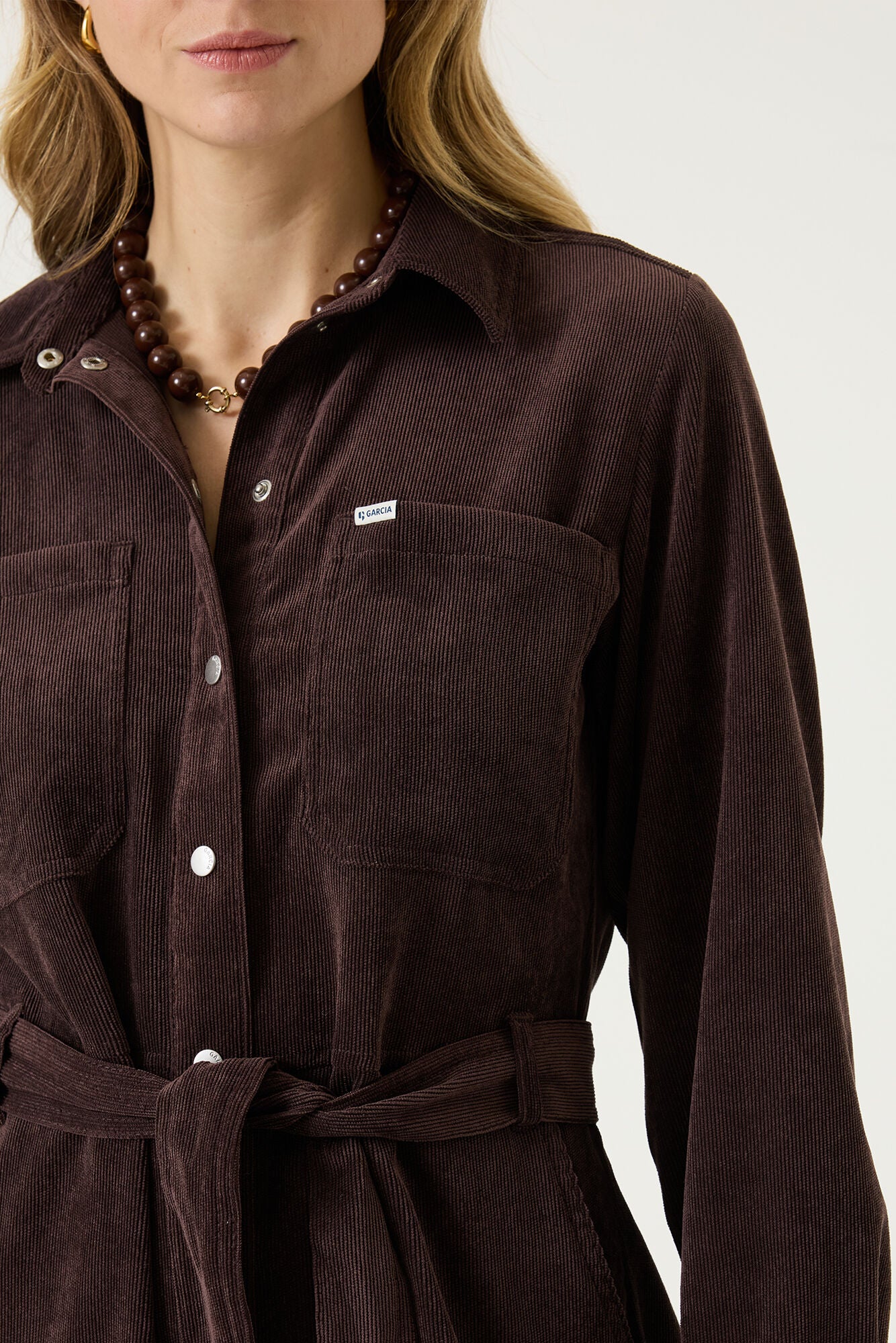 Gros plan sur le col, poche poitrine, l’étiquette logo et ceinture du robe manches longues brune foncé pour femme par Garcia