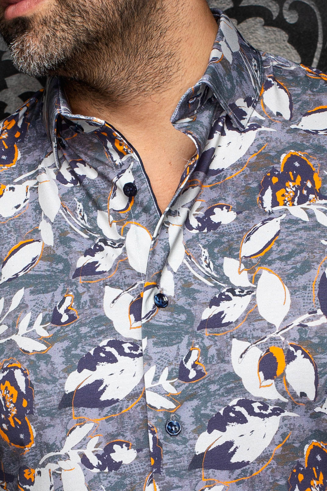 Gros plan du col de la chemise grise à imprimé floral blanc et orange avec boutons foncés pour homme par Au Noir