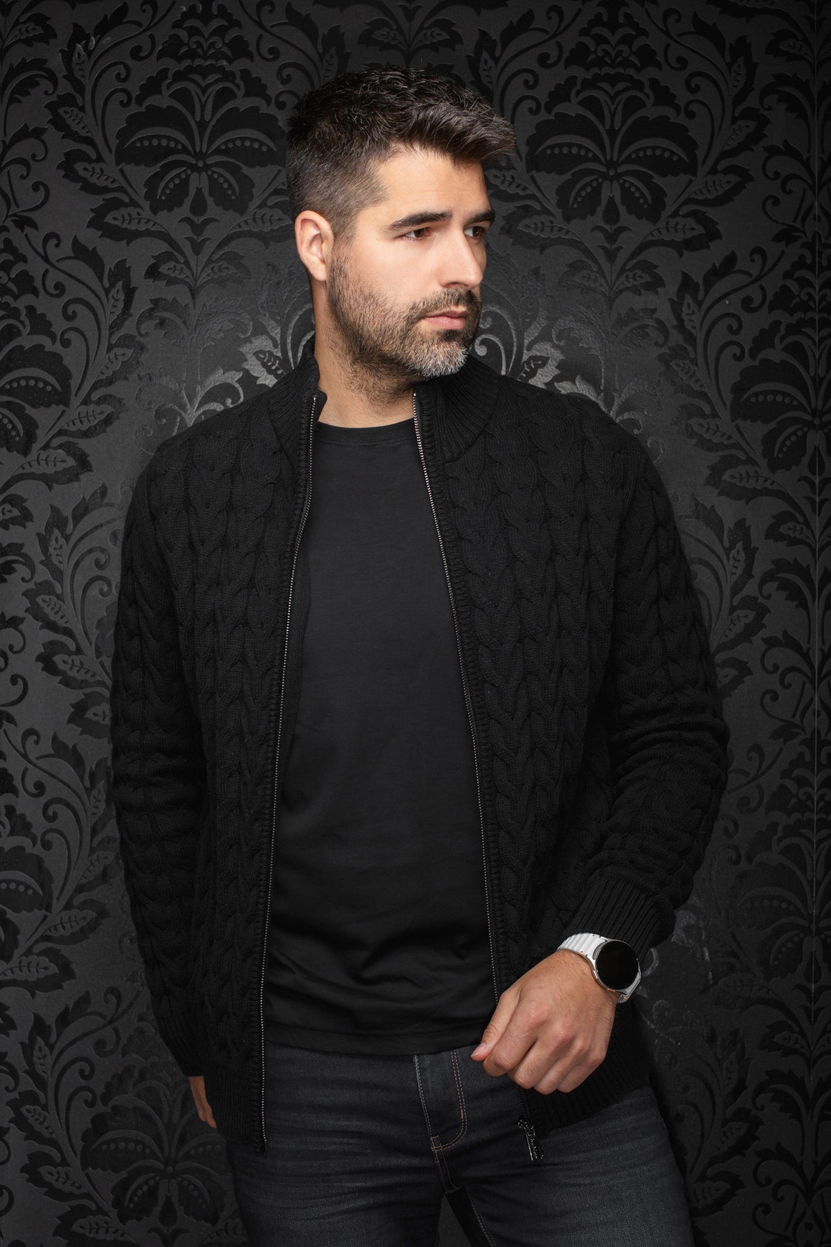 Vue de cote, vue inclinée d’une veste en mérinos noire en tricot torsadé portée ouverte, col pour homme par Au Noir