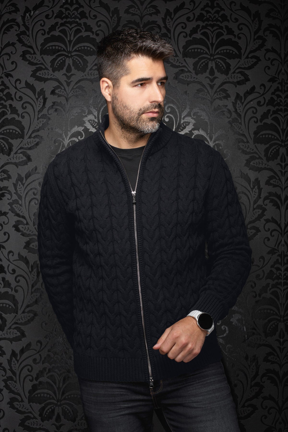Sur mannequin de face, la veste en mérinos zippée noire en tricot câblé avec bordures côtelées pour homme par Au Noir