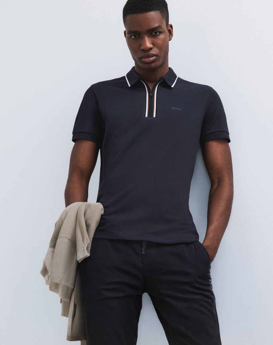 Polo BOSS marine à col zippé et détails contrastants, associé à un pantalon noir pour un look homme épuré.
