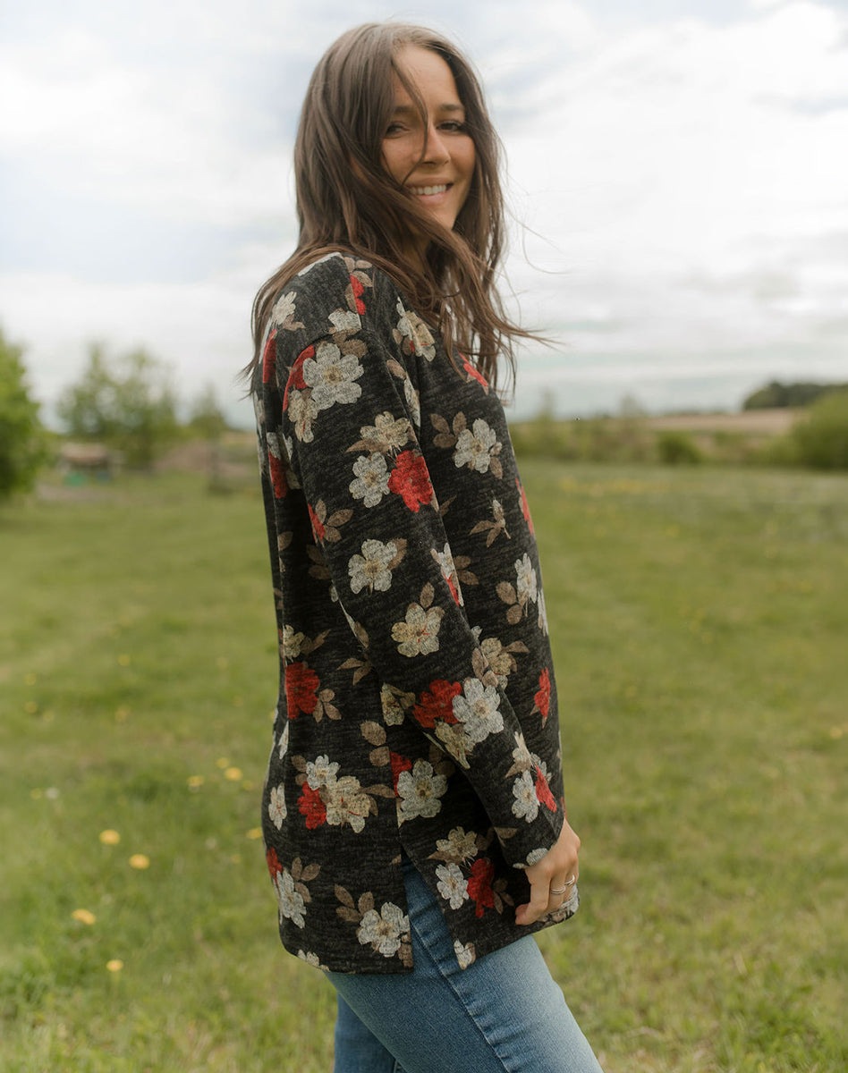 Tunique foncée à imprimé floral rouge et crème portée avec un jeans bleu, tenue féminine décontractée en extérieur.
